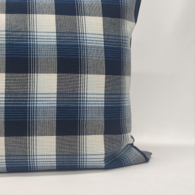 Almofada xadrez azul e cinza sobre superfície branca