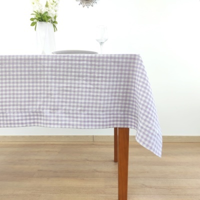 Toalha de mesa xadrez lilás e branco sobre mesa de madeira com prato e copo