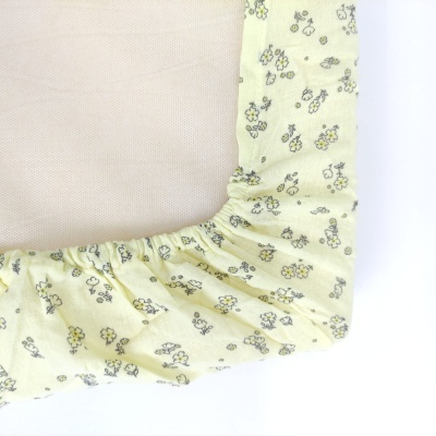 Capa elástica amarela com padrão floral aplicada numa estrutura de malha bege