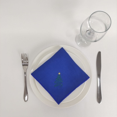Conjunto de pratos, talheres e copo com guardanapo azul decorado com árvore de Natal