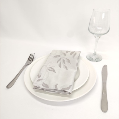 Conjunto de jantar com pratos brancos, guardanapo cinza com folhas e talheres prateados