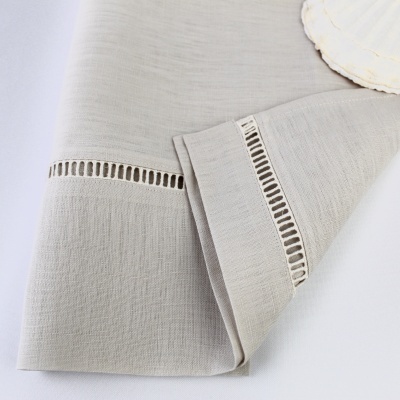 Guardanapo cinza claro com bordado rendilhado próximo da orla