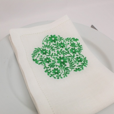 Guardanapo branco com bordado floral verde em prato branco