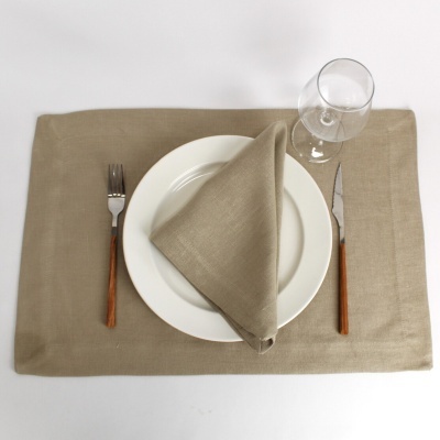 Mesa posta com individual bege, prato branco, guardanapo bege, talheres com cabo castanho e copo de vidro