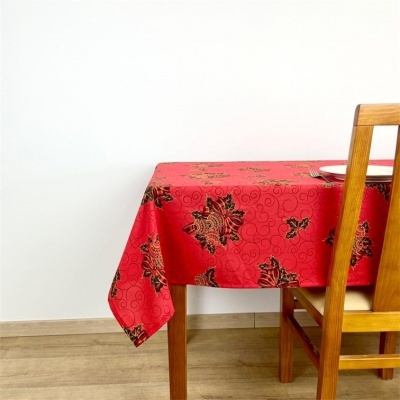 Toalha de mesa vermelha com padrões florais sobre mesa de madeira com cadeira ao lado