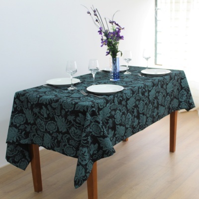 Toalha de mesa azul escura com padrão floral e arranjo de flores sobre mesa de madeira.