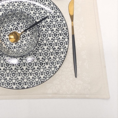 Conjunto de prato e taça em cerâmica azul e branco com colher dourada e preta em toalha bege