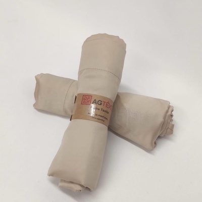 Dois tecidos bege enrolados com etiqueta AGTEX