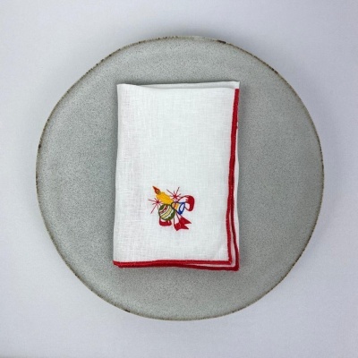 Guardanapo branco com borda vermelha e bordado colorido em prato cinza redondo