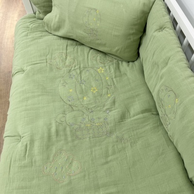 Roupa de cama verde claro com bordados de balão e nuvem em cama branca