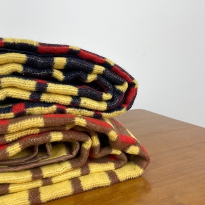 Mantas de malha dobradas com padrão riscado colorido sobre mesa de madeira