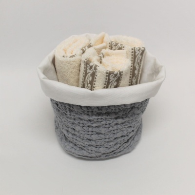 Cesto cinzento com toalhas creme enroladas dentro