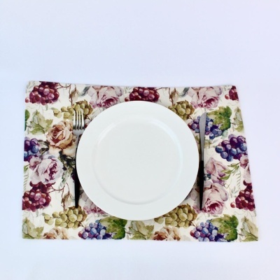 Lugar de mesa com padrão de uvas e flores, prato branco, garfo e faca