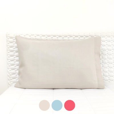 Travesseiro branco retangular sobre cama branca com cabeceira texturizada