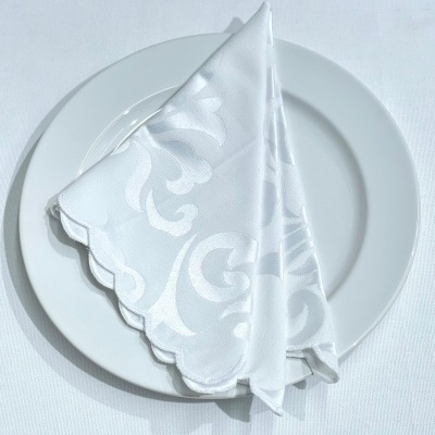 Guardanapo branco com padrão floral em prato branco sobre superfície branca