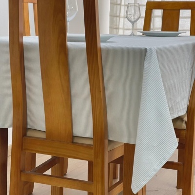 Mesa de refeição com toalha branca de riscas finas azuis e cadeiras de madeira clara