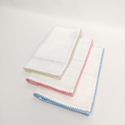 Três panos de tecido branco com bordas coloridas azul, rosa e bege