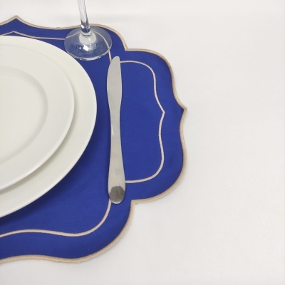 Jogo de jantar com pratos brancos, faca, copo e marcador de mesa azul com bordas douradas