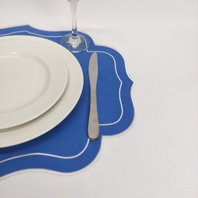 Conjunto de jantar com pratos brancos, individual azul e faca de metal