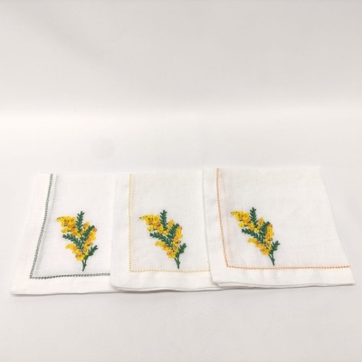 Três panos de cozinha brancos com bordados florais amarelos e verdes e costuras coloridas