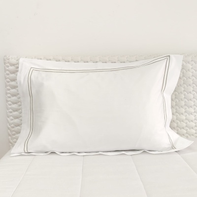 Almofada branca com bordado cinzento sobre almofada texturada branca