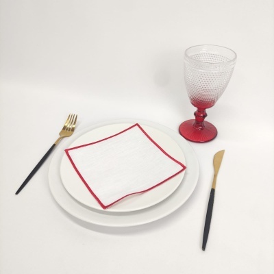 Conjunto de pratos, guardanapo, talheres e copo em fundo branco.