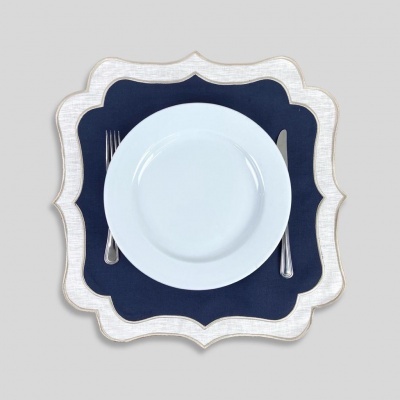 Prato branco com talheres sobre descanso de prato branco e azul escuro