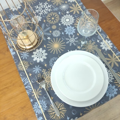 Tapete de mesa com flocos de neve brancos e dourados em fundo cinza e utensílios de jantar