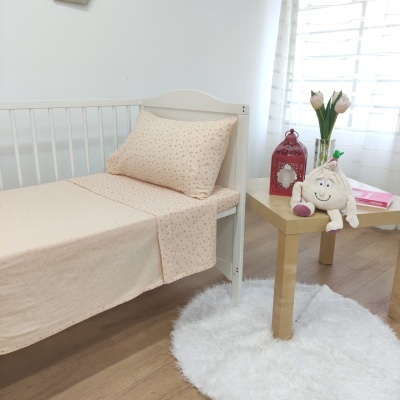 Cama branca com roupa de cama bege e mesa de madeira com flores e peluche
