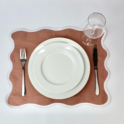 Conjunto de jantar com pratos brancos, talheres, copo e individual cor de laranja com borda branca