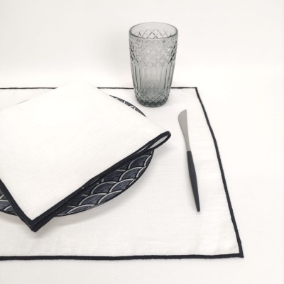 Conjunto de jantar com prato azul, guardanapo branco, copa de vidro cinzento e faca com cabo preto