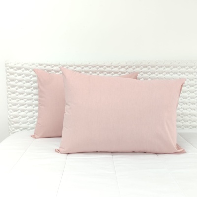 Três almofadas cor de rosa sobre cama branca com cabeceira acolchoada