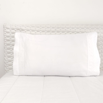 Travesseiro branco com fronhas decorativas em cama branca
