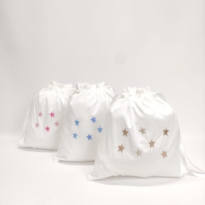 Três sacos de tecido branco com estrelas coloridas