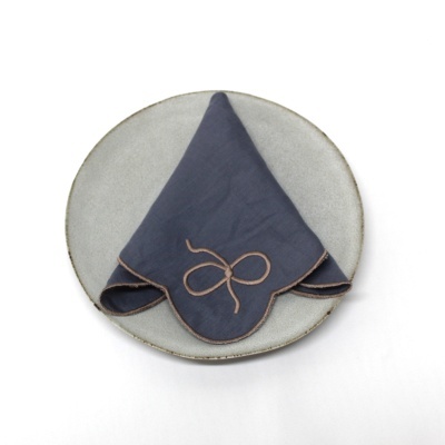 Prato cinzento com guardanapo azul escuro bordado por cima.