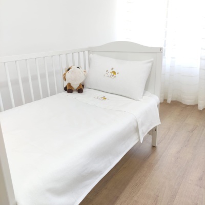 Cama de bebé branca com roupa de cama branca e peluche de tigre