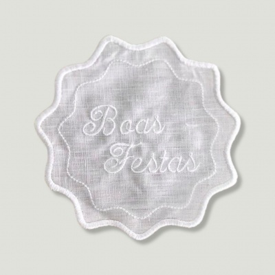 Aplicação em tecido branco bordada com texto 'Boas Festas'
