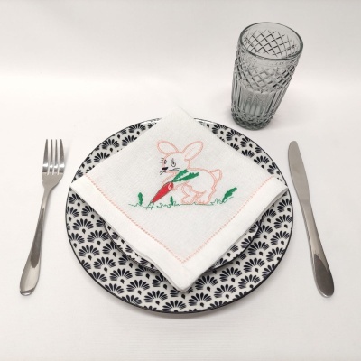 prato decorado, talheres em aço, copo transparente e guardanapo bordado com coelho