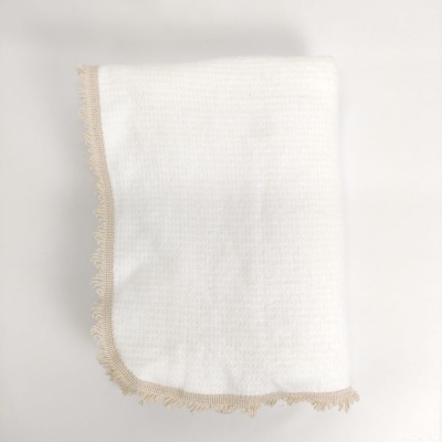 Manta ou toalha branca com borda bege e franjas, sobre fundo branco