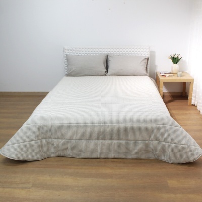 Cama de casal com colcha e almofadas bege quadriculadas em quarto minimalista