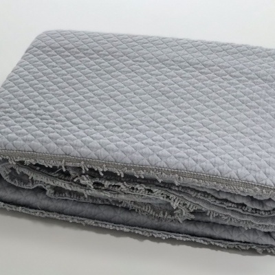 Manta cinza clara com padrão matelassé dobrada