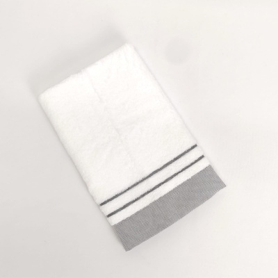 Toalha branca com detalhes cinzentos dobrada