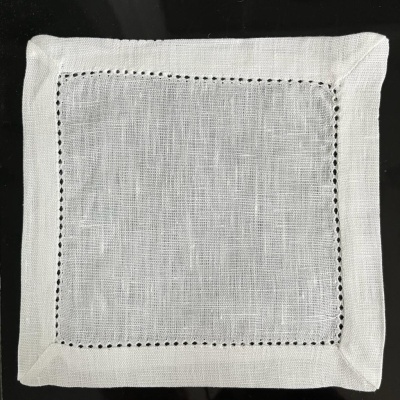 Guardanapo quadrado branco em linho com borda vazada sobre fundo preto