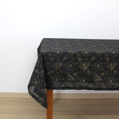 Toalha de mesa preta com padrão dourado sobre mesa de madeira