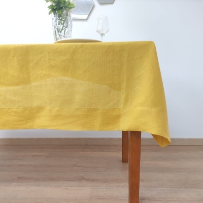 Toalha de mesa amarela sobre mesa de madeira com vaso e copo