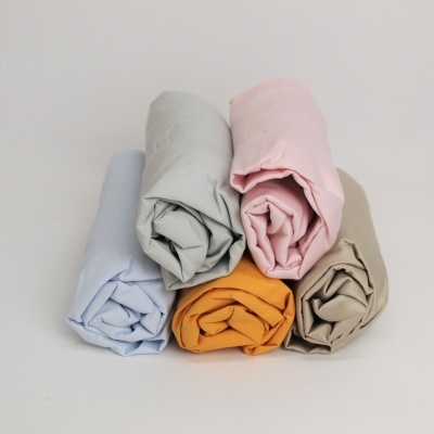 Cinco tecidos enrolados em várias cores claras sobre fundo branco.