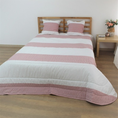 Cama de casal com roupa de cama às riscas rosa claro e branco e cabeceira de madeira