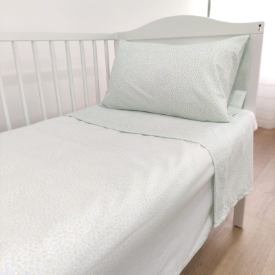 Cama branca de criança com lençol e fronha brancos com padrão geométrico discreto