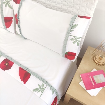 Conjunto de roupa de cama branca com folhos e padrão floral vermelho e verde