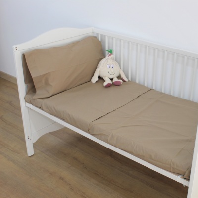 Cama branca de criança com roupa de cama castanha e boneco de pelúcia